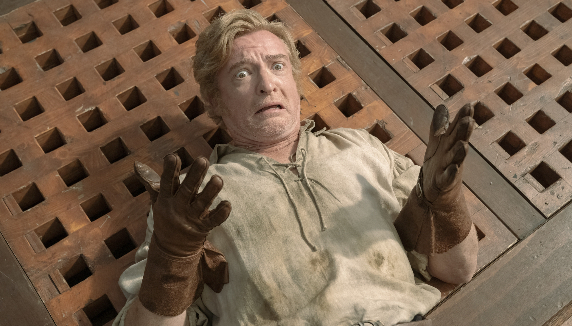 Pirate captain Stede Bonnet (Rhys Darby) lying on his back on the deck and holding up his hands with a particularly dismayed and hapless goofy look on his face in season 2 of Our Flag Means Death